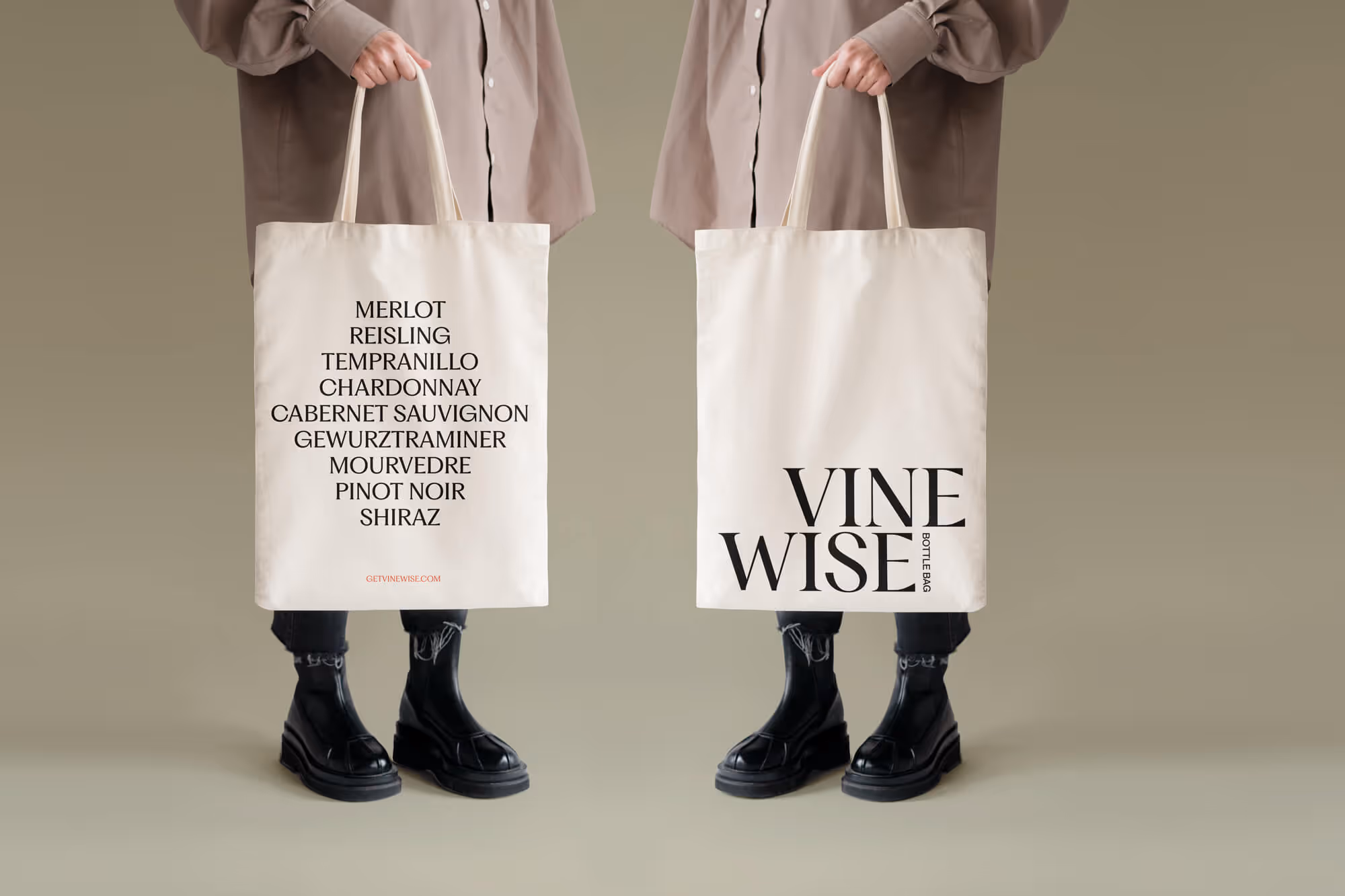 Person wearing black boots and beige shirt holding a cream tote bag with wine variety names on one side and VINE WISE text on the other.